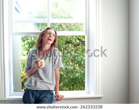 Portrait of a happy woman laughing with a cup of coffee at home