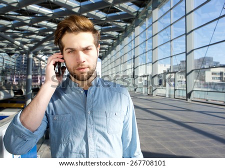 Close up portrait of a serious young man talking on mobile phone inside building