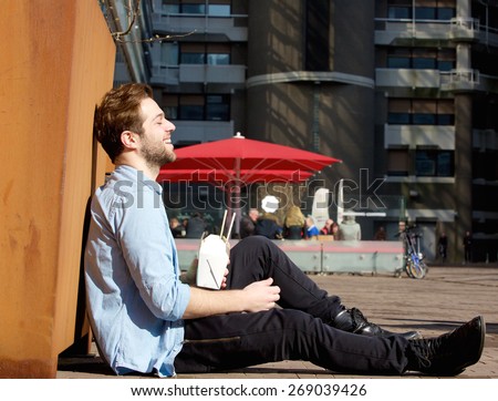 Portrait of a happy man relaxing outdoors with chinese takeaway
