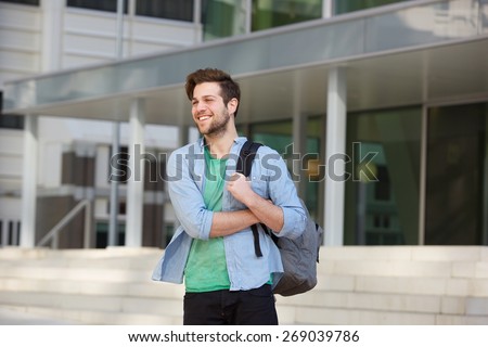 Portrait of a happy male college student standing outside with bag