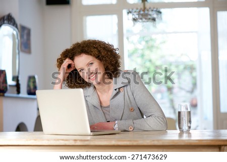 Portrait of a smiling older woman sitting at table using laptop