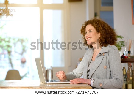 Side portrait of a happy middle aged woman using laptop at home