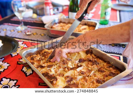 Close up elderly woman hands holding knife to cut a slice of homemade food