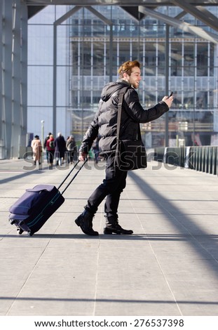Portrait of a handsome young man walking with bag and mobile phone at station