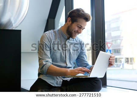 Portrait of a smiling man using laptop