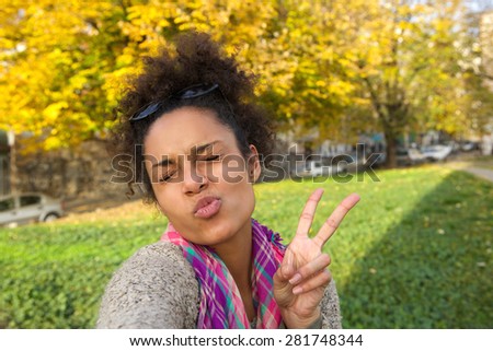 Selfie portrait of a cute girl making face with peace sign