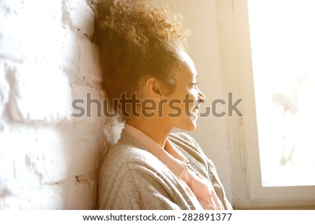 Close up portrait of a young african american woman smiling and looking out of window