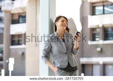 Portrait of a businesswoman standing in the city with cell phone