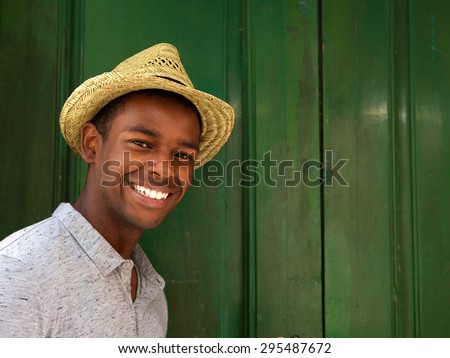Close up portrait of a handsome young man smiling with hat on green background