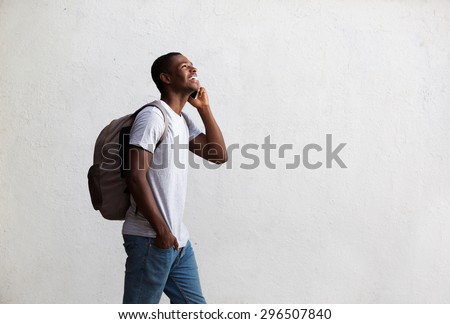 Side portrait of a happy student walking and talking on mobile phone