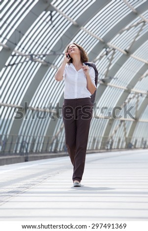 Full body portrait of a walking business woman talking on mobile phone