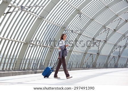 Side portrait of a smiling business woman walking with bag at station