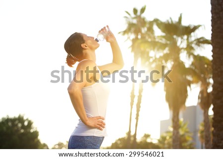 Side portrait of a sports woman drinking water from bottle after workout
