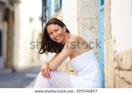 Side portrait of a happy woman sitting outside in summer dress