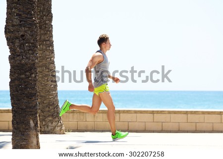 Young fitness man running by the sea side