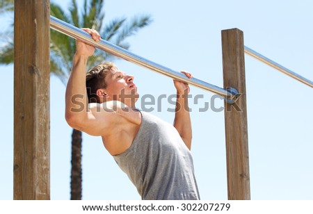 Young sports guy pull up exercise routine outdoor