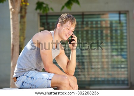 Side portrait of a young man smiling and listening to mobile phone call