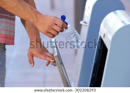 Close up male hand putting plastic bottle in recycling bin