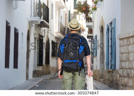 Portrait of the back of traveling man holding map in town