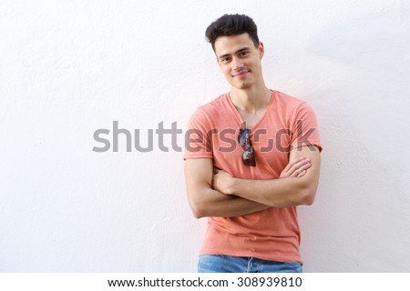 Portrait of a confident young man smiling with arms crossed against white background