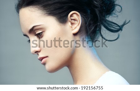 Closeup beauty portrait of a young beautiful brunette woman. Muse. Profile, looking down.