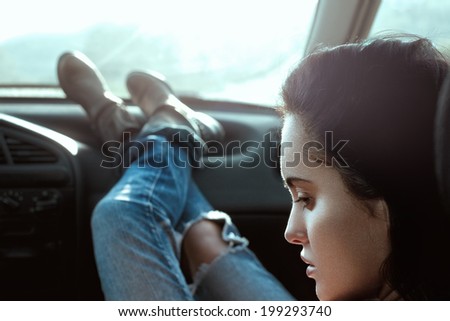 Fashion portrait of a beauty brunette girl in blue jeans sitting in the car. Summer days.