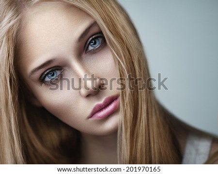 Closeup beauty portrait of young blonde woman with with long curly and makeup. Smoky eyes.