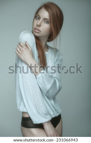 Fashion studio portrait of stunning red-haired model with long straight hair in underwear.
