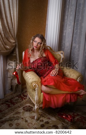 Glamorous girl seat on the chair in red dress