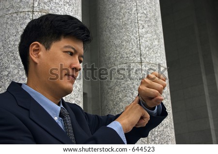 Asian Man in A Business Suit Looking at His Watch