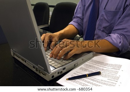 Typing On The Computer - Close-up of a man\'s hands typing on the computer in the office with some documents, blank paper and pen next to him