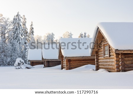 Small snowy cosy log cabins in row at very snowy winter day
