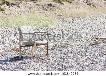 Old worn out chair outside on a land covered with small stones