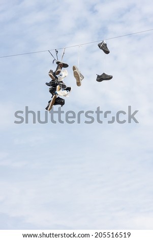 Many old worn boots or shoes hang on an electric cable