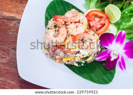 Fried rice with salted egg and shrimp on banana leaf decor by vegetable and orchid