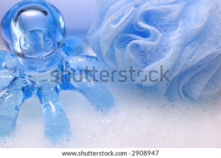 Blue net bath sponge and octopus shaped body massager in soap bubbles
