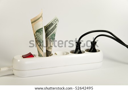 Concept on rising energy price. Shown is a household power socket with a switch and some plugs and wires and some US Dollar banknotes.