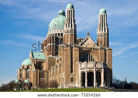 The Basilica of the Sacred Heart in Brussels ranks fifth among the largest churches in the world. The large Art Deco building is catched in the sunlight against a light-blue sky with some clouds.