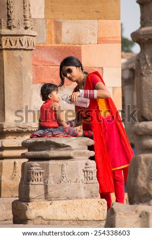 DELHI, INDIA - NOVEMBER 4: Unidentified woman with unidentified child drinks water at Qutub Minar complex on November 4, 2014 in Delhi, India. Qutub Minar is the tallest minar in India