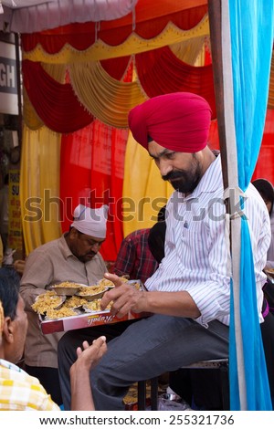 DELHI, INDIA - NOVEMBER 5: Unidentified man gives away rice during Guru Nanak Gurpurab celebration on November 5, 2014 in Delhi, India. This festival celebrates the birth of the first Sikh Guru.