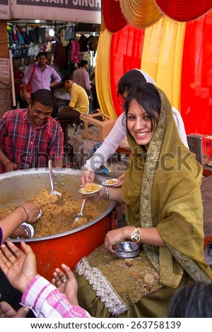 DELHI, INDIA - NOVEMBER 5: Unidentified woman gives away rice during Guru Nanak Gurpurab celebration on November 5, 2014 in Delhi, India. This festival celebrates the birth of the first Sikh Guru.
