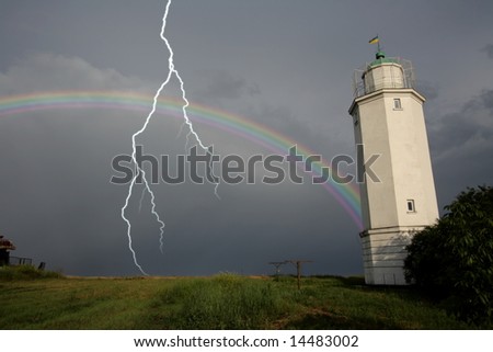 Rainbow against a lighthouse after a thunder-storm with lightning flash