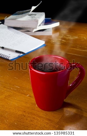 Cup of coffee with text books and notebook in background