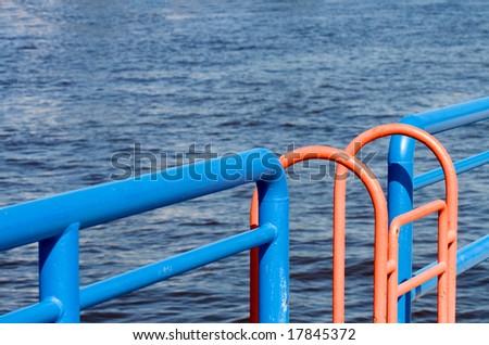 An orange ladder interrupts the straight blue line of the rails along a Great Lakes channel wall