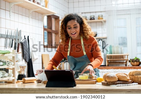 Young Afican American woman learning online  cooking class via tablet computer in kitchen at home