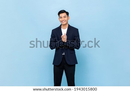 Smiling young handsome southeast Asian man clapping hands impressively in light blue studio isolated background Stock foto © 
