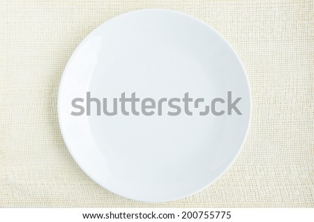 Empty white dish on cream fabric table mat