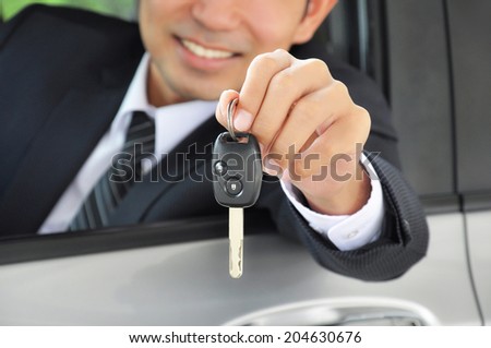 Businessman showing a car key - car sale & rental business concept