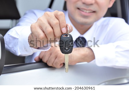 Smiling man showing a car key - car sale & rental business concept