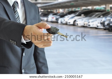 Businessman hand giving a car key - car sale & rental business concept